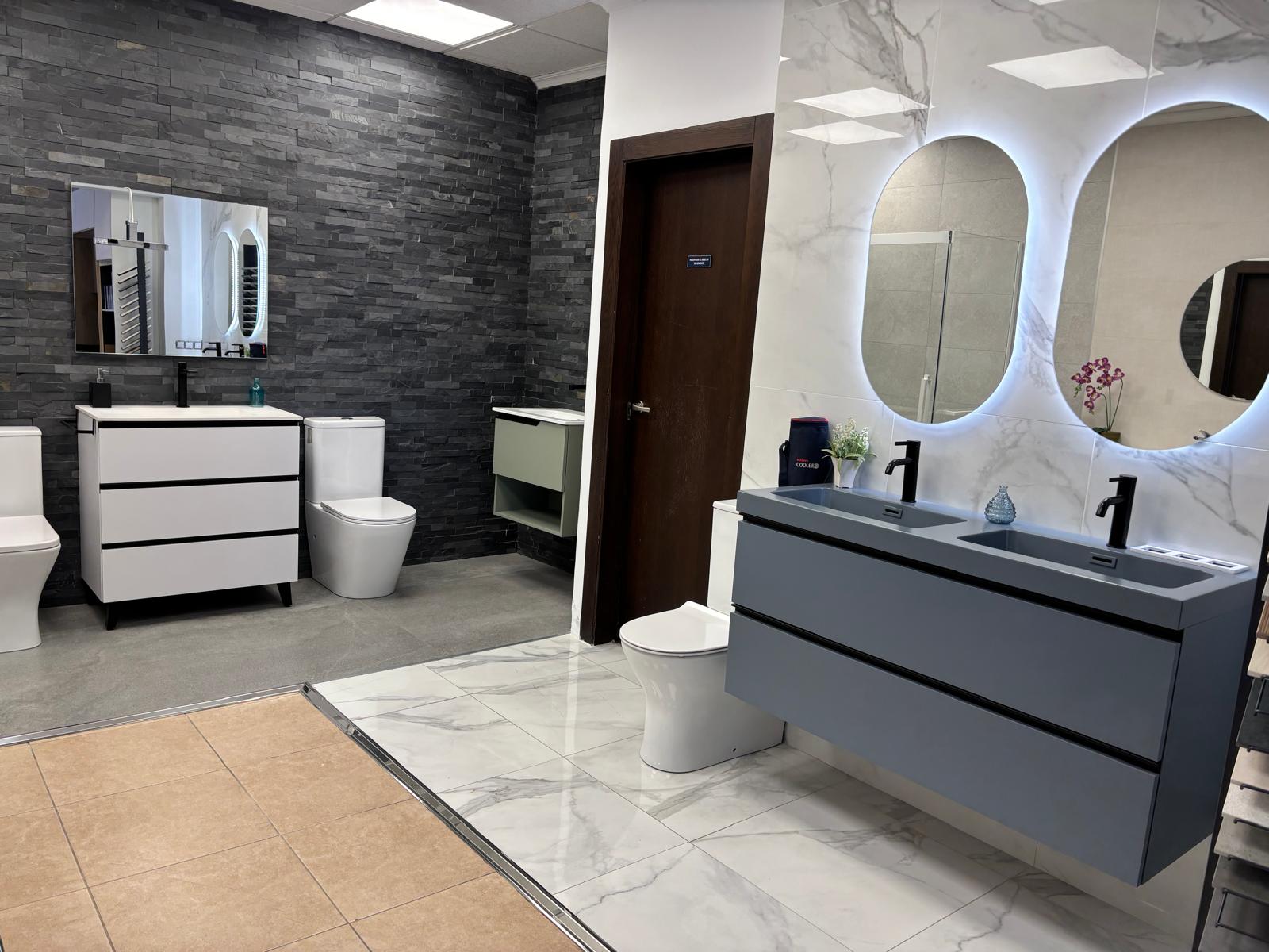 Exposición de baños con mueble de madera, sanitarios y espejo redondo iluminado