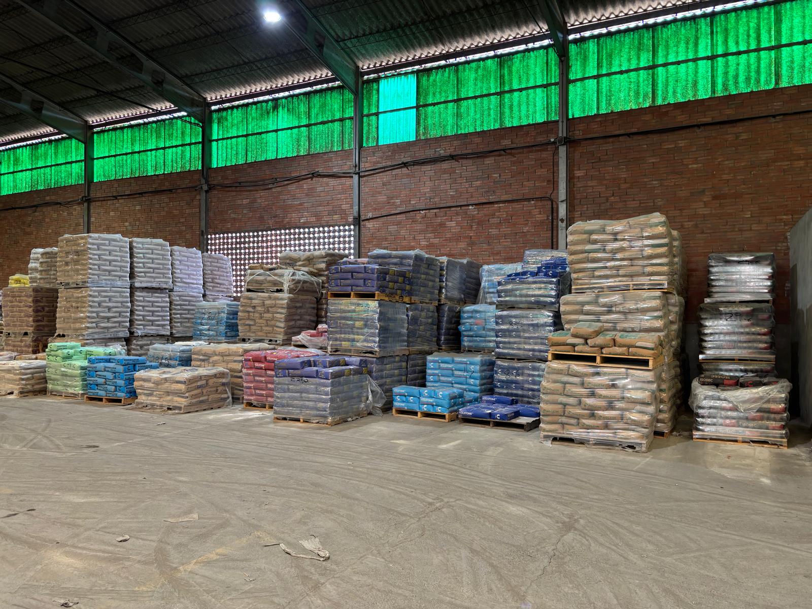 Nave de almacén con sacos de cemento y mortero apilados por color